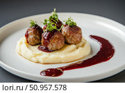 A deconstructed display of Swedish meatballs artfully arranged. Lingonberry sauce and creamy mashed potatoes add a modern touch to this minimalist Nordic culinary presentation. Стоковое AI-изображение, AI-художник Nart / Фотобанк Лори