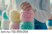 A close-up of a person's hands gently holding a stack of colorful pastel yarn skeins, ideal for craft project inspiration or promoting knitting and crochet hobbies. Стоковое AI-изображение, AI-художник Данила Большаков / Фотобанк Лори