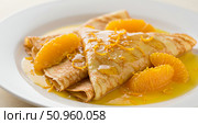 Delicious crepe suzette with orange segments and zest on white plate for breakfast or dessert. Sweet morning meal. Стоковое AI-изображение, AI-художник Анжелика Самсонова / Фотобанк Лори