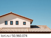 House Exterior. Roof Window. Second floor among blue sky. Mansard attic. Newly build houses. Gable roof with skylight, asphalt roofing, shingles. Residential Home. Vinyl Siding. Polymeric roof-tiles. Стоковое AI-изображение, AI-художник Марина Демидюк / Фотобанк Лори