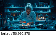 Blonde female scientist meticulously working in a blue-lit laboratory, conducting research with advanced equipment for medical breakthroughs. Стоковое AI-изображение, AI-художник Данила Большаков / Фотобанк Лори