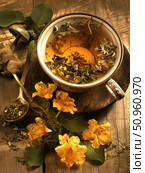 Atmospheric composition with a cup of herbal tea and yellow flowers lying on an old wooden table. The frame also features a metal spoon with dry leaves and a tea bag. Warm light adds coziness and tranquility to the scene, creating a feeling of home warmth and natural harmony. Ideal for themes: natural products, herbal medicine, healthy lifestyle, aromatherapy, tea ceremonies, coziness and retro aesthetics. Стоковое AI-изображение, AI-художник Анна Кривицкая / Фотобанк Лори
