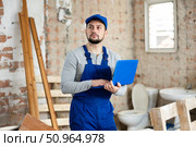 Builder handyman checking plan of house renovation on laptop. Стоковое фото, фотограф Яков Филимонов / Фотобанк Лори