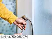 Flexible shower hose connection process shows installer tightening hose onto shower mixer outlet using open-end wrench with clear detail of threading at attachment point. Стоковое фото, фотограф Владимир Григорьев / Фотобанк Лори