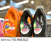 Two bottles of Ariel laundry detergent are on a shelf next to a Tide bottle. Russia. Moscow. 02.08.25. Редакционное фото, фотограф Ярославский Максим / Фотобанк Лори