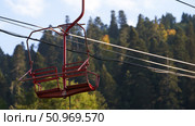 A fragment of the cable car. The two-seater chairlift number 13 in the air against the backdrop of picturesque autumn mountains. Стоковое фото, фотограф Роман Дзюбало / Фотобанк Лори