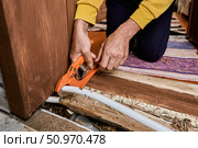 Plumber uses pipe cutter to remove leaking section from plastic tubing during replacement process at area where visible damage occurred earlier. Стоковое фото, фотограф Владимир Григорьев / Фотобанк Лори