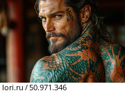 Portrait of a man with bright Japanese-style tattoos on his back and neck. He has a thick beard, long hair, a piercing gaze and a tattoo on his face. The image combines brutality and charisma, conveys confidence, strength and style. Ideal for themes related to male character, tattoo culture, subculture and the beauty industry. Стоковое AI-изображение, AI-художник Анна Кривицкая / Фотобанк Лори