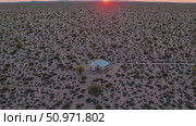 Aerial view of a lonely house in the desert at sunset with mountains on the horizon, conveying concepts of isolation, tranquility, and the vastness of nature. Стоковое AI-видео, аниматор Данил Руденко / Фотобанк Лори