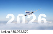 Airplane flying through 2026 numbers above clouds under clear blue sky concept. Стоковое AI-изображение, AI-художник lyudmila Soloveva / Фотобанк Лори