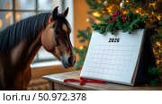 A chestnut horse stands next to a mockup of a 2026 calendar decorated with pine branches and red berries placed on a wooden table outdoors at sunset. Стоковое AI-изображение, AI-художник lyudmila Soloveva / Фотобанк Лори