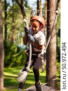 Climbing High in the Sky at an Exciting Outdoor Rope Park for Young Adventurers. Редакционное фото, фотограф Aleksandr Golubev / Фотобанк Лори
