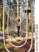 Exploring the Heights in a Thrilling Rope Park Adventure Among Towering Trees and Sunshine. Редакционное фото, фотограф Aleksandr Golubev / Фотобанк Лори