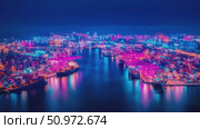 Illuminated harbor at night featuring cargo ship activity and vibrant city lights, showcasing a busy port terminal beneath a deep blue sky. Стоковое AI-видео, аниматор Данила Большаков / Фотобанк Лори