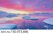A majestic arctic panorama at sunrise, with brilliant pink and purple clouds casting colorful reflections on the calm, ice-strewn ocean. Стоковое AI-видео, аниматор Данила Большаков / Фотобанк Лори