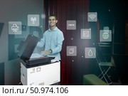 Young man using a multifunction printer in an office environment, showcasing modern technology and digital integration. Стоковое фото, фотограф Сергей Толмачёв / Фотобанк Лори