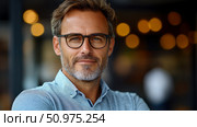 Portrait of a man with glasses and graying hair, smiling gently against a blurred background. Стоковое AI-изображение, AI-художник Данила Большаков / Фотобанк Лори