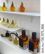 Perfume bottles on white shelves showcasing various fragrances and colors. Стоковое фото, фотограф Анастасия Золотницкая / Фотобанк Лори