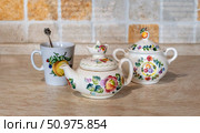 Tea party preparation. Beautiful: teapot, sugar bowl and cup with spoon on the kitchen table. Handmade items. Selective focus. Стоковое фото, фотограф Анищенко Геннадий / Фотобанк Лори