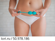 Faceless woman in white panties holding the Kegel trainer for strengthening the intimate muscles of the vagina. Vaginal balls with a displaced center of gravity of a mint color. Sex toy. Стоковое фото, фотограф Михаил Решетников / Фотобанк Лори