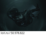 Futuristic 3D rendering of a translucent embryo floating in darkness, symbolizing artificial life and advanced biotechnology. Стоковая иллюстрация, иллюстратор Happyphotons / Фотобанк Лори