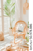 Sunlit Bohemian Interior Design: Rattan Chair, Laptop, and Plants. Стоковое AI-изображение, AI-художник Данила Большаков / Фотобанк Лори
