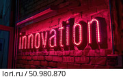 A neon sign spelling out innovation casts a pink glow against the dark bricks of a wall, suggesting creativity and advancement. Стоковое AI-изображение, AI-художник Данила Большаков / Фотобанк Лори