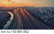 Enjoy a stunning aerial perspective of a busy city highway illuminated by sunset lights as traffic flows smoothly along the routes. Стоковое AI-видео, аниматор Данила Большаков / Фотобанк Лори