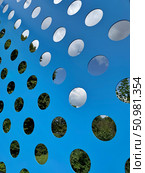 Bright blue wall with circular openings showing trees and sky through the holes. Concept of: Architectural perspective. Стоковое фото, фотограф Ольга Петрова-Апостолова / Фотобанк Лори