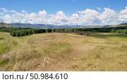 Bannoe Center, Russian Federation - July 27, 2025: Expansive golden grassland landscape under a bright blue sky with fluffy clouds and distant mountains, showcasing the beauty of nature and tranquility. Редакционное видео, видеограф Ирина Ручушкина / Фотобанк Лори