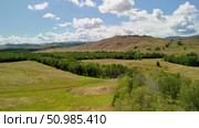 Bannoe Center, Russian Federation - July 27, 2025: Expansive aerial view of lush green forest and rolling hills under bright blue sky showcasing natural beauty and tranquility. Редакционное видео, видеограф Ирина Ручушкина / Фотобанк Лори