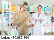Pregnant woman buyer scans pills qr code with woman pharmacist. Стоковое фото, фотограф Яков Филимонов / Фотобанк Лори