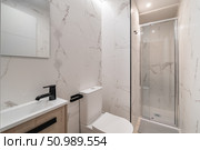 Modern bathroom with marble walls, a glass shower, and a sleek sink. The design is minimalist and contemporary, featuring neutral colors and clean lines. Стоковое фото, фотограф PAv / Фотобанк Лори