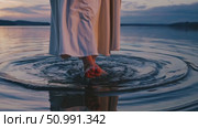 Religious leader wearing white robe walking gracefully across tranquil lake surface at sunset, creating soft ripples amid peaceful natural scenery. Стоковое AI-видео, аниматор Данил Руденко / Фотобанк Лори