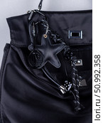 Close-up of a stylish leather bag accessory featuring a detailed leather charm. Accompanying the set are black keychains with sea star motifs and a decorative cord adorned with beads. Стоковое фото, фотограф Виталий Сова / Фотобанк Лори