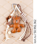 Close-up of a stylish leather bag accessory featuring a detailed leather bear charm no white bag. Стоковое фото, фотограф Виталий Сова / Фотобанк Лори