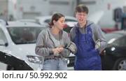 Male mechanic advises young woman client on repairing of car in car service station. Стоковое видео, видеограф Яков Филимонов / Фотобанк Лори