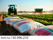 Tractor cultivate field, tractor spraying vineyard with fungicide, sprayer machine, trailed by tractor, sprinkles pesticides among rows of vineyards. Стоковое AI-изображение, AI-художник Ирина Старикова / Фотобанк Лори