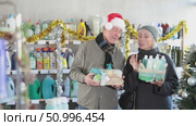 Senior spouses studies label and choose shower cosmetic present, packaged in basket on Christmas Eve. Стоковое видео, видеограф Яков Филимонов / Фотобанк Лори