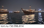Festive lights adorning traditional dhows illuminating Dubai Creek, mirroring city's glittering skyline against dark night waters. Стоковое AI-видео, аниматор Данил Руденко / Фотобанк Лори