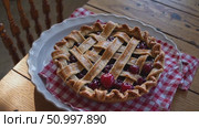 Homemade cherry pie cooling on white plate, resting over red checkered napkin against weathered wooden surface, evoking nostalgic kitchen comfort. Стоковое AI-видео, аниматор Данил Руденко / Фотобанк Лори