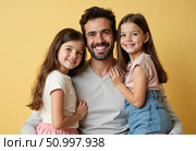 A joyful father is embraced by his two daughters, both smiling brightly and showcasing their playful personalities Generative AI. Стоковое AI-изображение, AI-художник Юлия Петровская / Фотобанк Лори