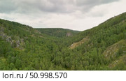 Scenic landscape featuring steep mountains and dense forests in a valley, with dramatic cloud formations above, highlighting the tranquility of the natural environment. Стоковое видео, видеограф Ирина Ручушкина / Фотобанк Лори