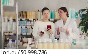 Positive asian woman client choosing liquid syrup and scan QR code on label at pharmacy, young woman pharmacist consulting customer. Стоковое видео, видеограф Яков Филимонов / Фотобанк Лори