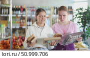 Two friends discuss buying sweets and the calorie content of desserts at the supermarket. Customers choose natural desserts in a European store. Стоковое видео, видеограф Яков Филимонов / Фотобанк Лори