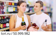 Man with wife near display of alcohol drinks in hypermarket doubt choice. Стоковое видео, видеограф Яков Филимонов / Фотобанк Лори