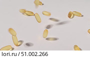 Close-up of falling transparent yellow capsules over white backdrop. Food supplements containing omega 3 and fish oil. Стоковое видео, видеограф Михаил Решетников / Фотобанк Лори