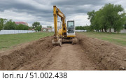 Excavator digging trench in field under cloudy sky. Стоковое AI-видео, аниматор Юрий Поздников / Фотобанк Лори