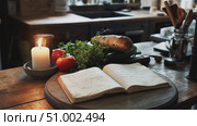 Recipe book resting on wooden table near fresh tomatoes, herbs, root vegetable, and burning candle, creating warm ambiance in rustic kitchen environment. Стоковое AI-видео, аниматор Данил Руденко / Фотобанк Лори