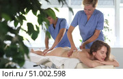 Back massage in four hands simultaneously - two professional masseurs treating young woman. Стоковое видео, видеограф Яков Филимонов / Фотобанк Лори